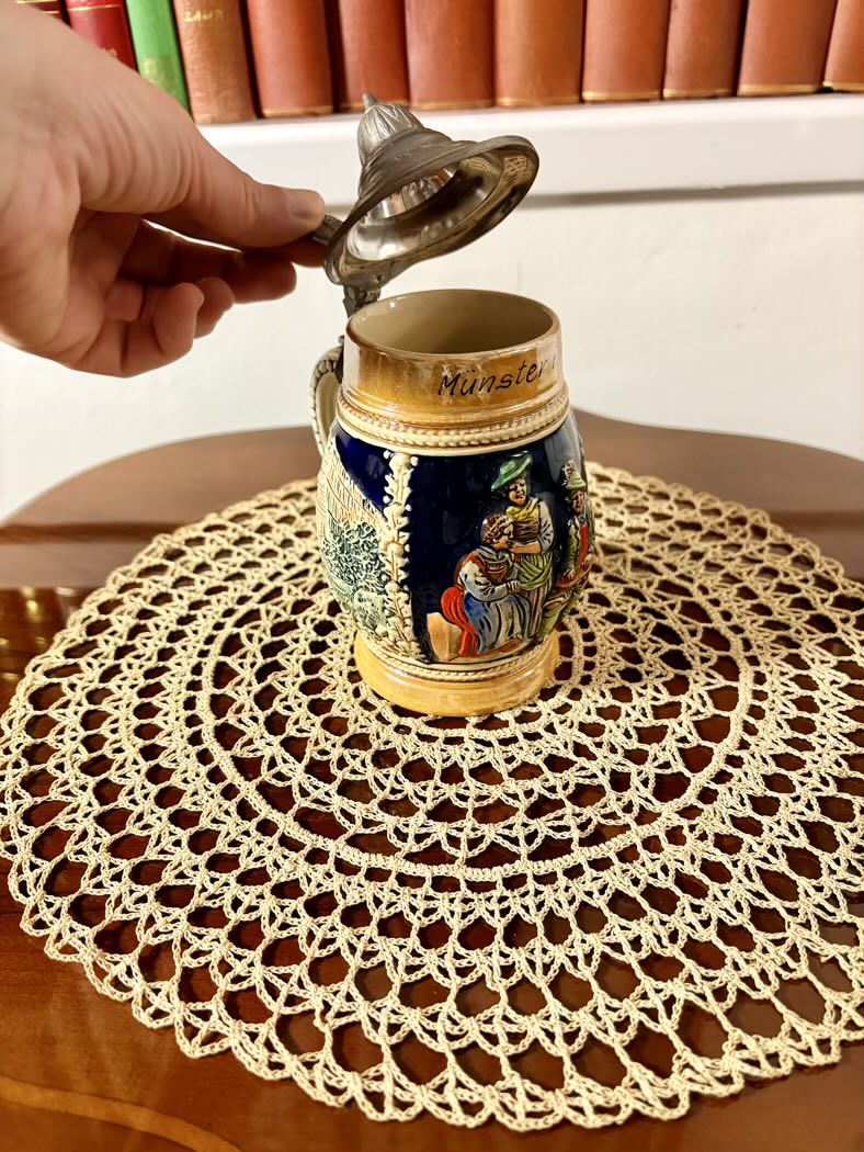 Decorative beer stein with intricate designs on a lace doily