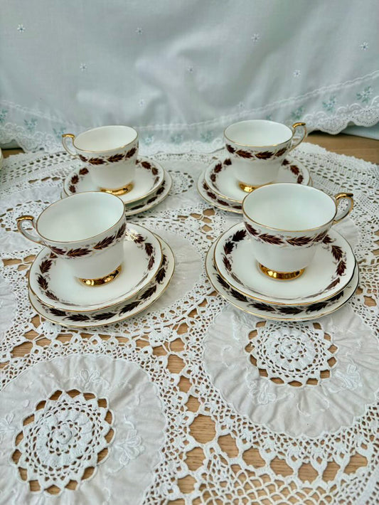 Set of four vintage-style tea cups and saucers on a lace tablecloth.