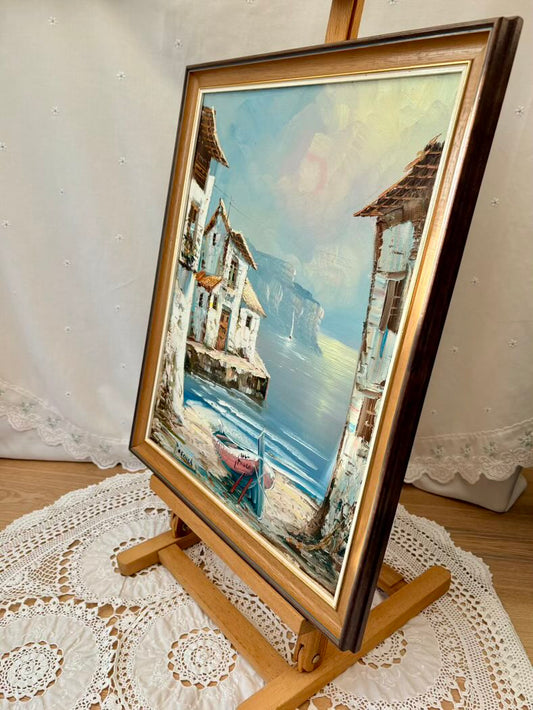Framed painting of a coastal scene on a lace-covered surface