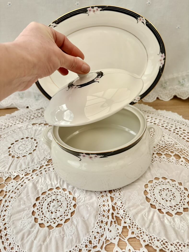 White enameled pot with a lid on a lace tablecloth