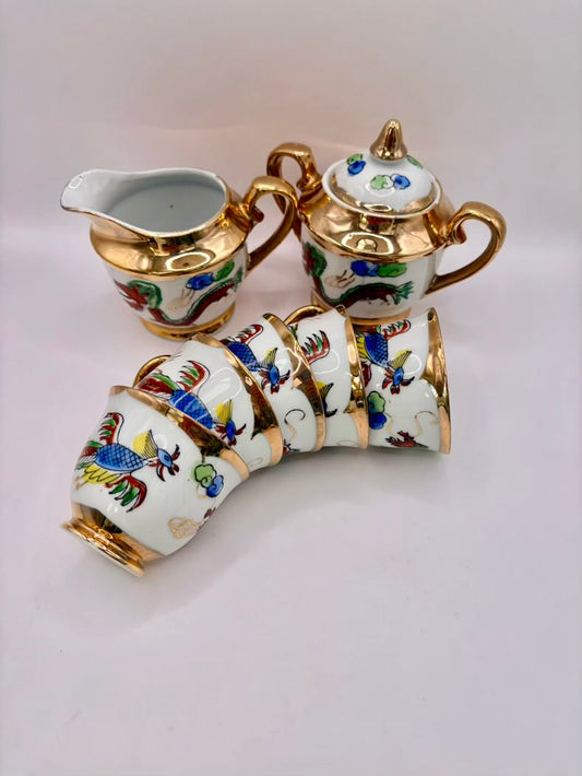 Decorative ceramic teapot, creamer, and sugar bowl set with floral patterns on a white background