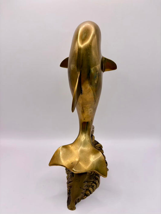 Brass dolphin sculpture on a white background