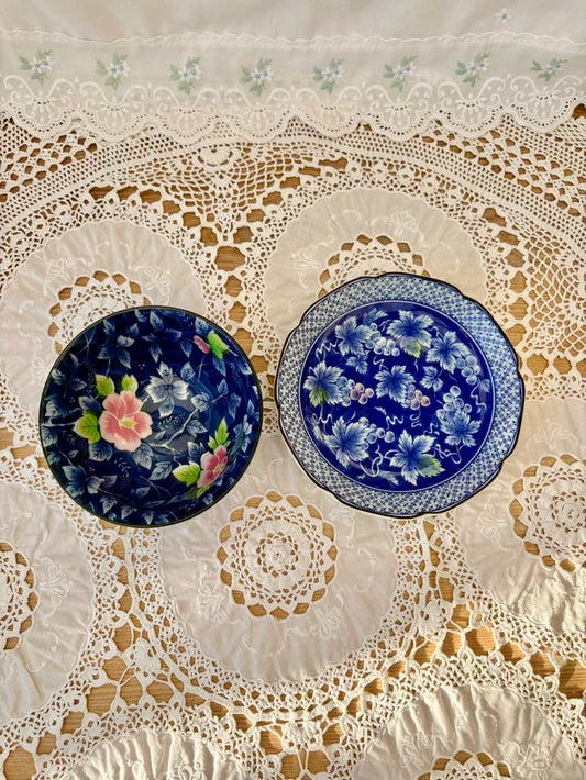 Two floral-patterned plates on a lace tablecloth