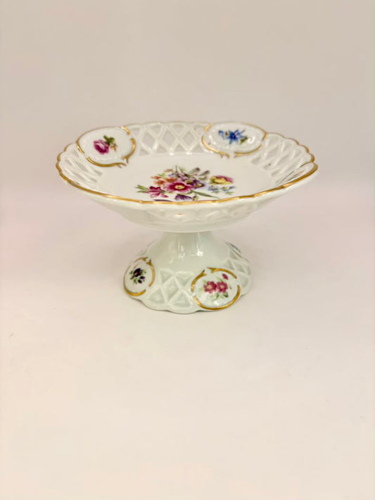 Decorative ceramic pedestal bowl with floral patterns on a plain background