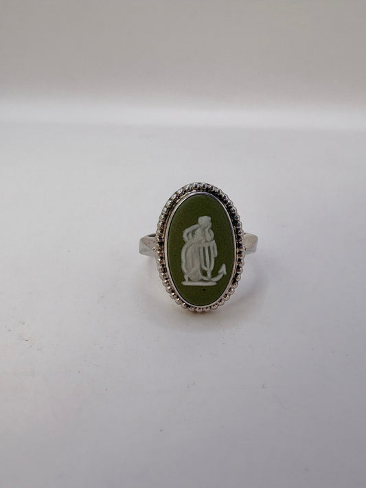 Silver ring with a green oval stone and engraved design on a white background