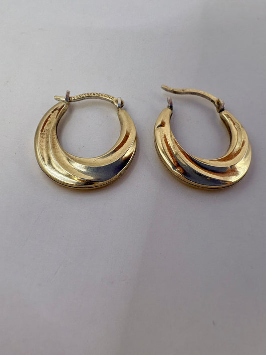 Gold hoop earrings on a light gray background