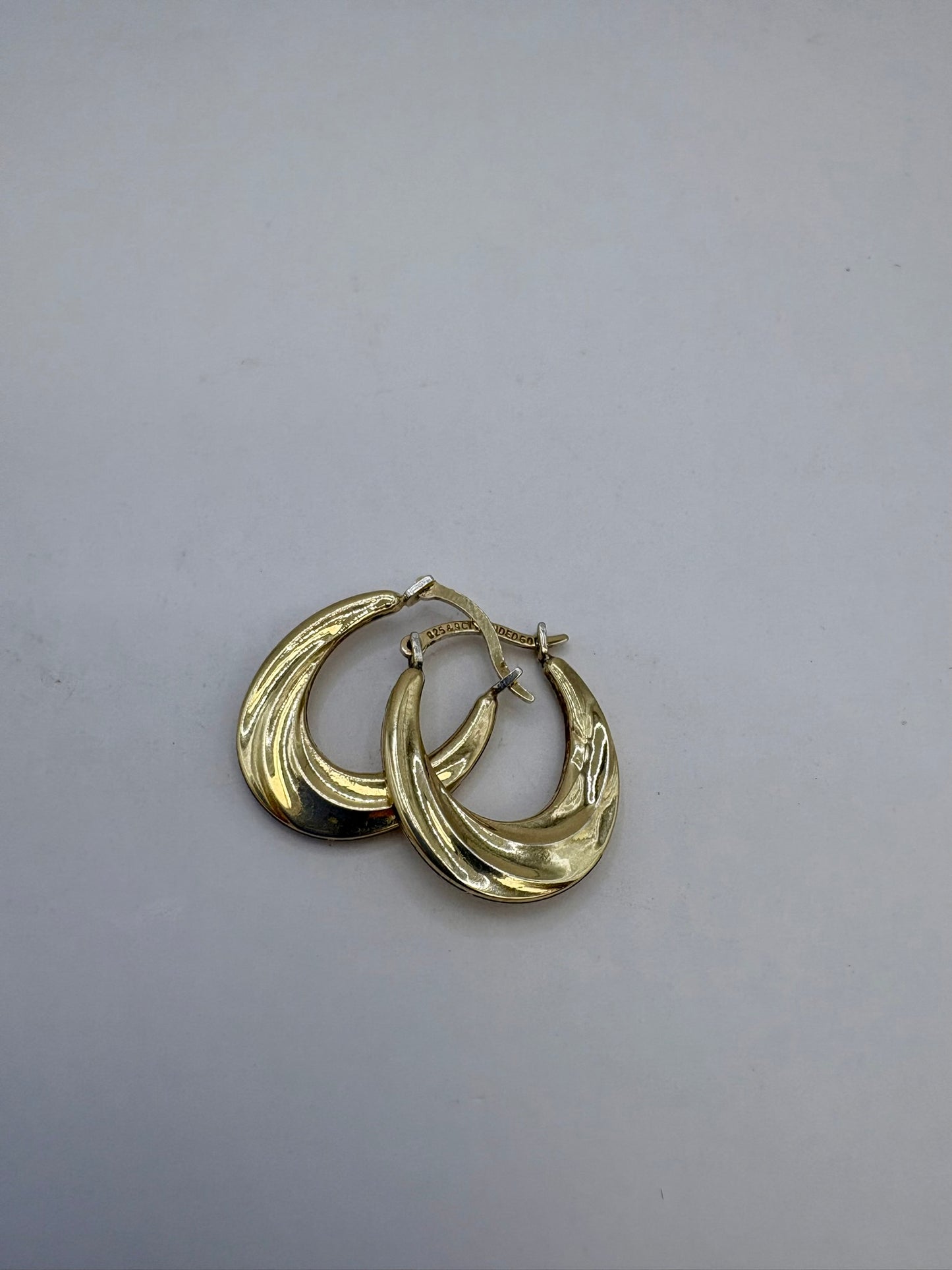 Pair of gold hoop earrings on a light gray background