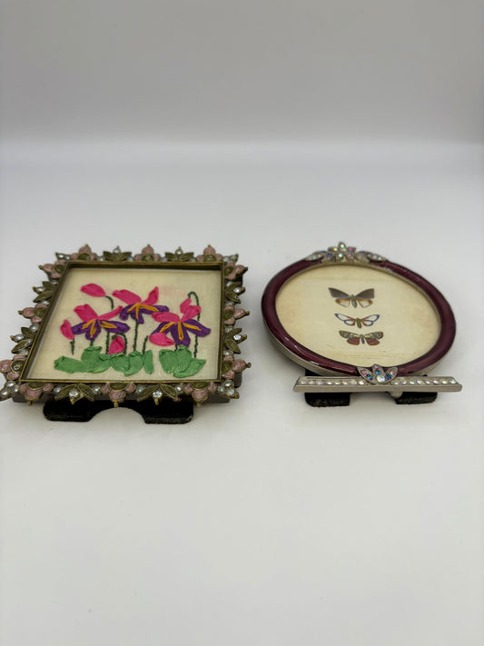 Two embroidered pieces in decorative frames on a white background