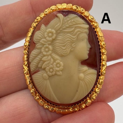 Gold-framed cameo with a profile of a woman held between fingers