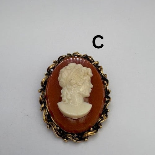 Cameo brooch with profile portrait in a gold frame on a gray background
