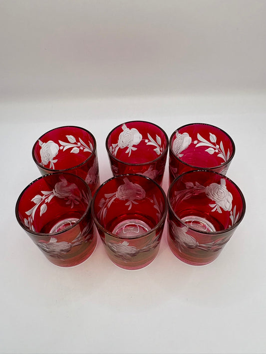 Set of six red glass tumblers with white floral patterns on a white background