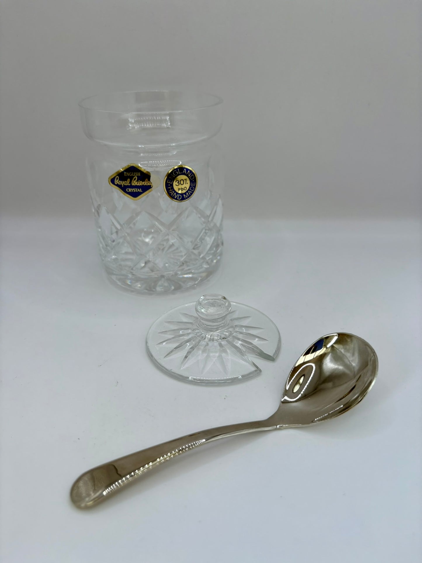 Clear glass container with a lid and a silver spoon on a white background