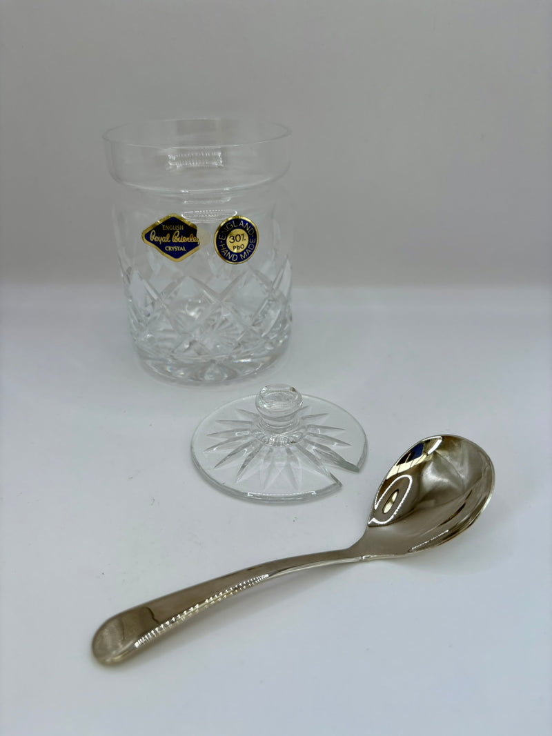 Clear glass container with a lid and a silver spoon on a white background