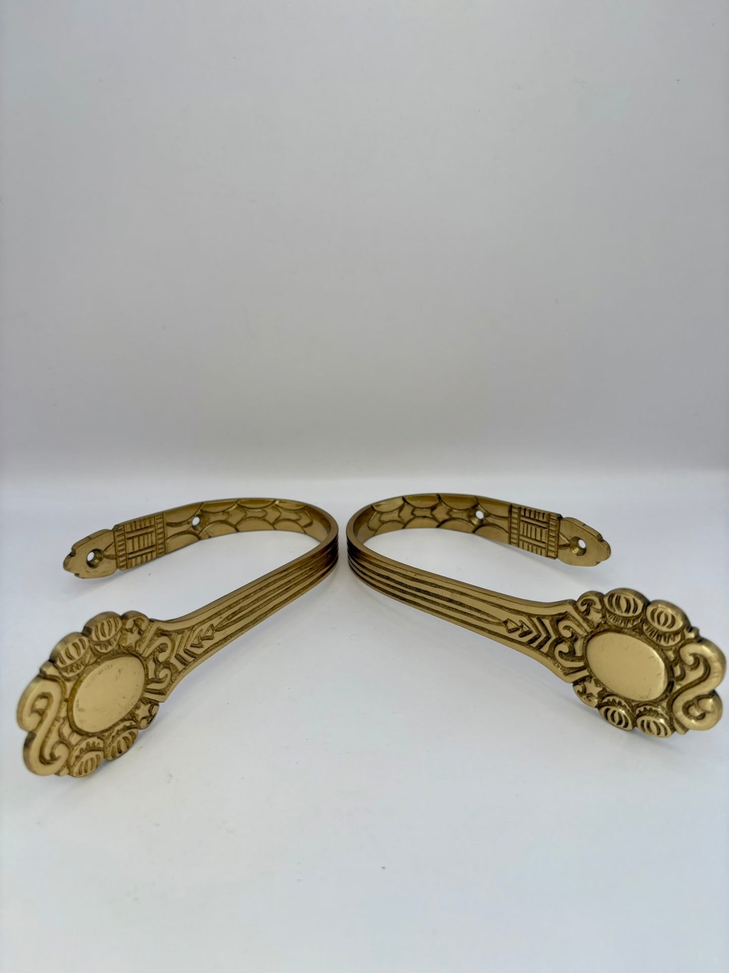 Pair of ornate brass brackets on a white background