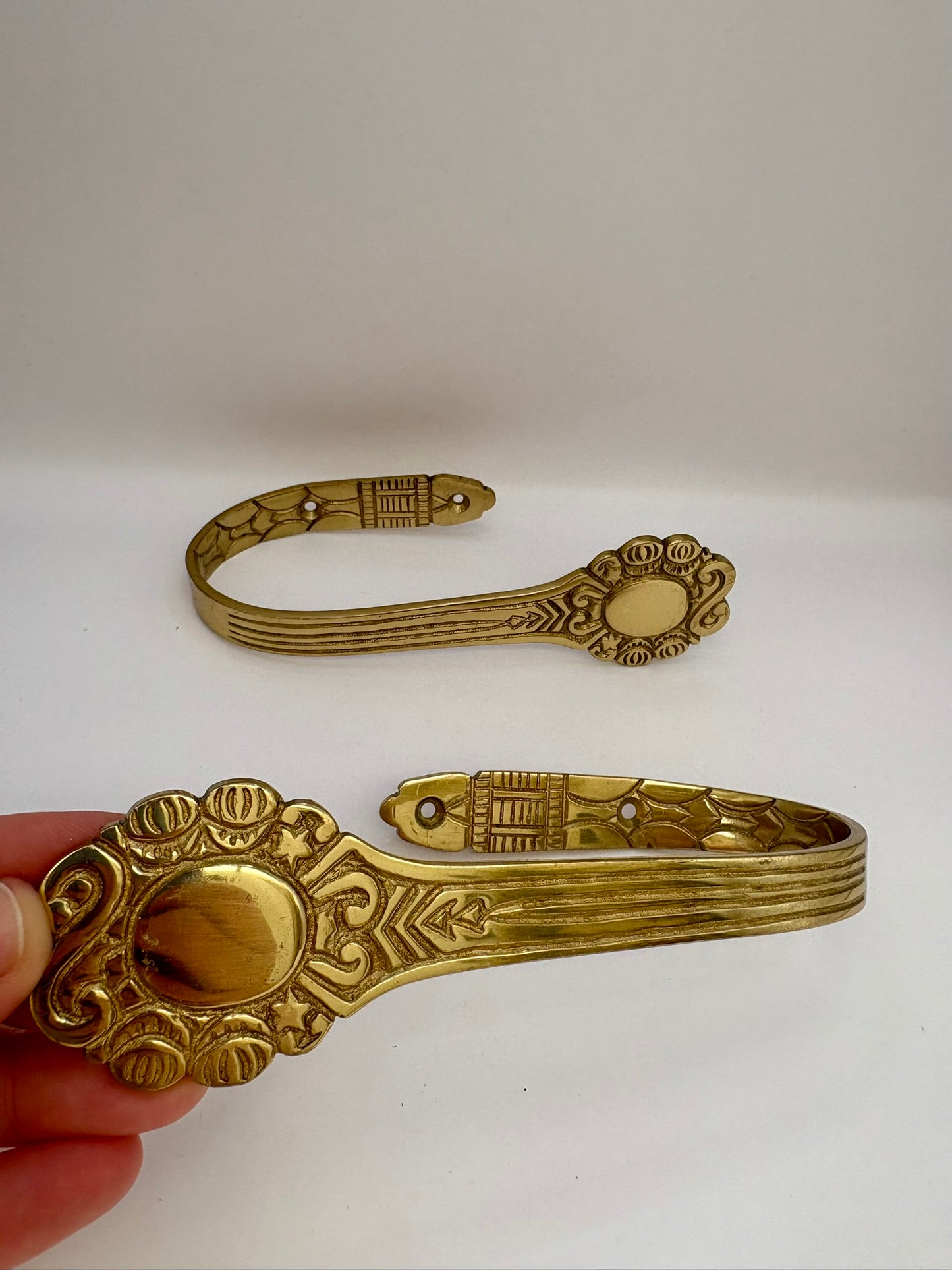 Decorative brass clip held by a hand on a white background