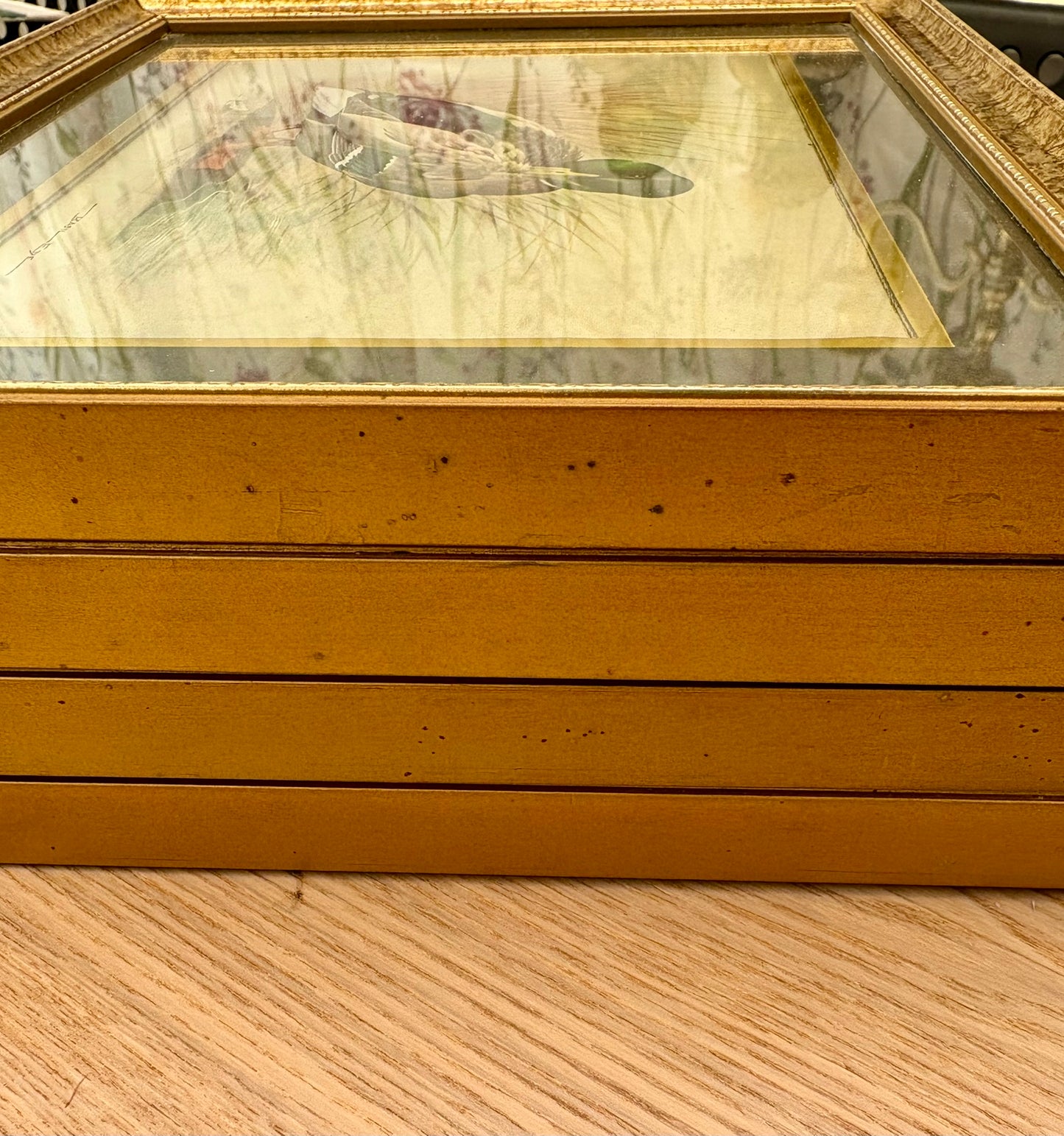 Gold-framed picture on a wooden surface