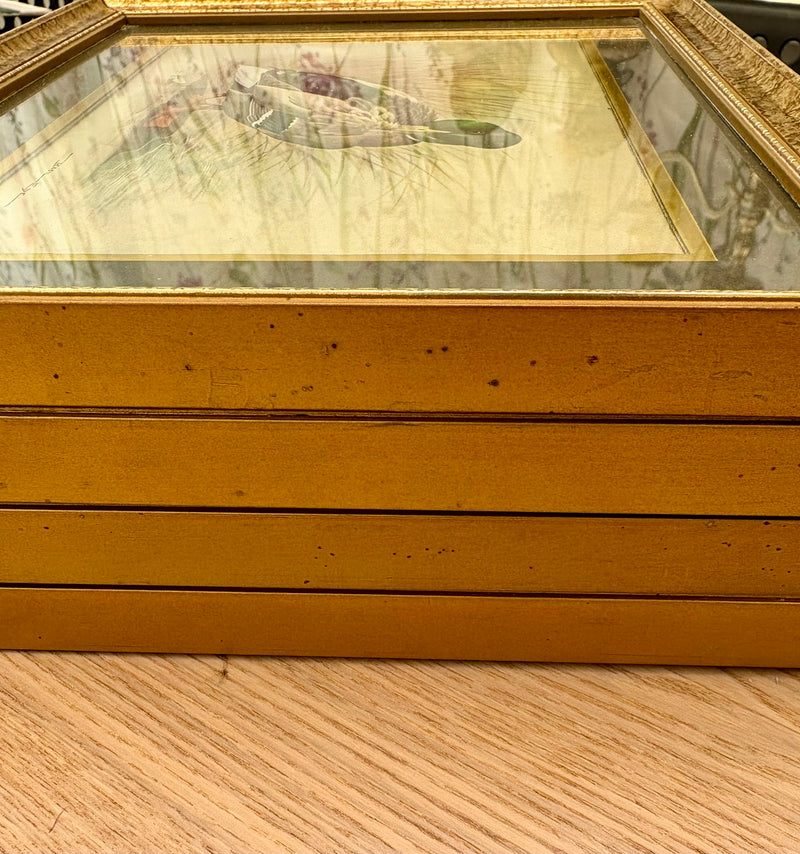 Gold-framed picture on a wooden surface