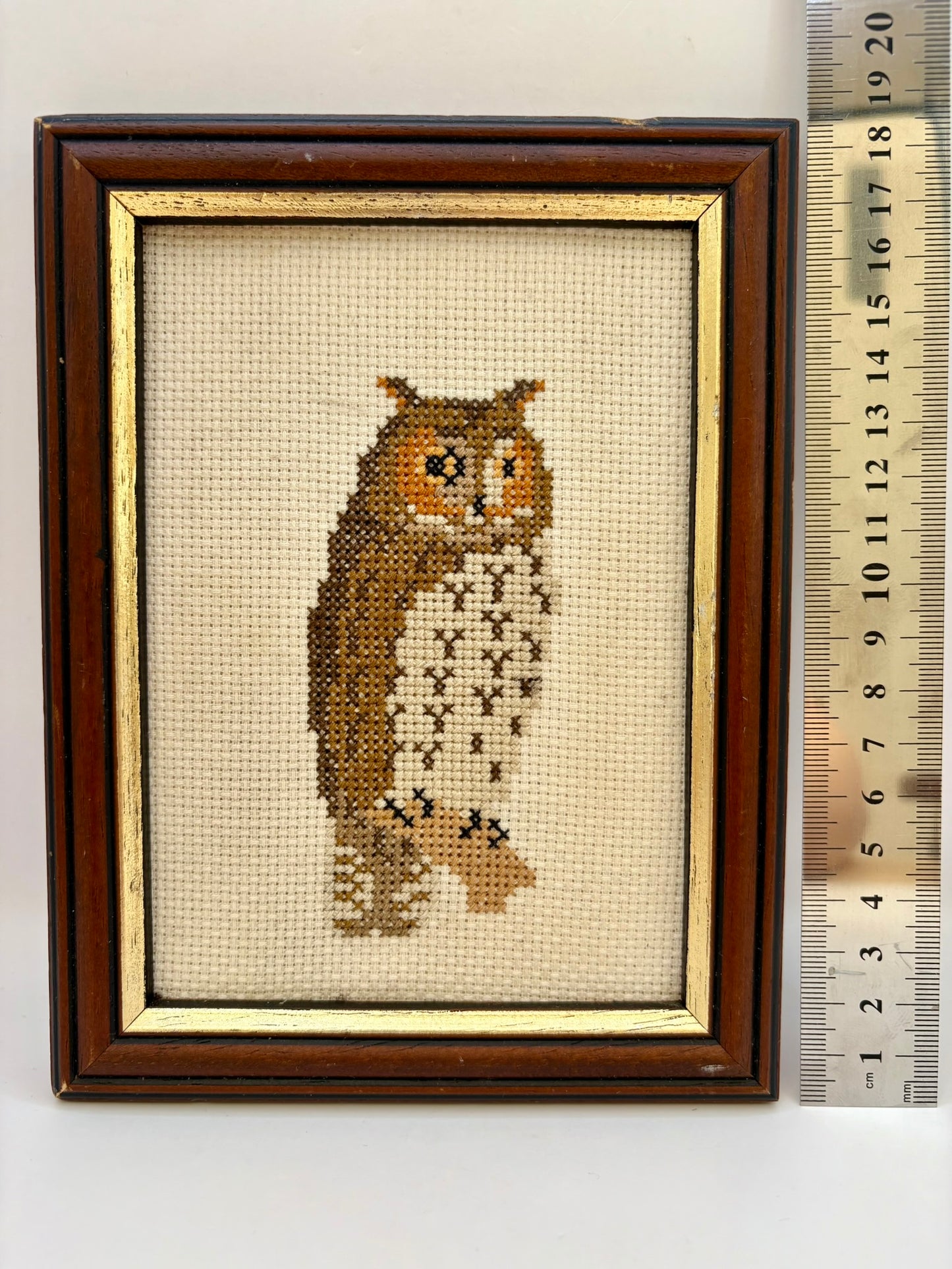 Framed cross-stitched owl on fabric with a wooden frame and ruler for scale.
