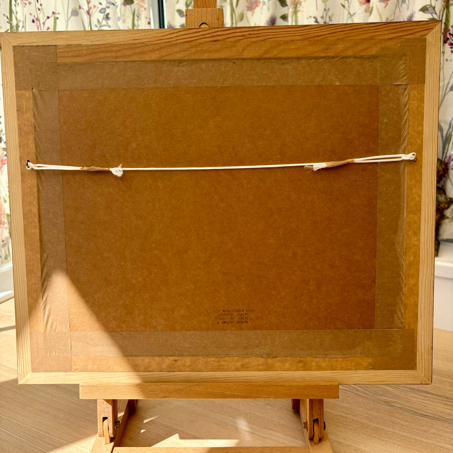 Back view of a wooden picture frame with a brown mat on an easel.