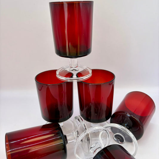 Set of red glass tumblers with a clear base on a white background