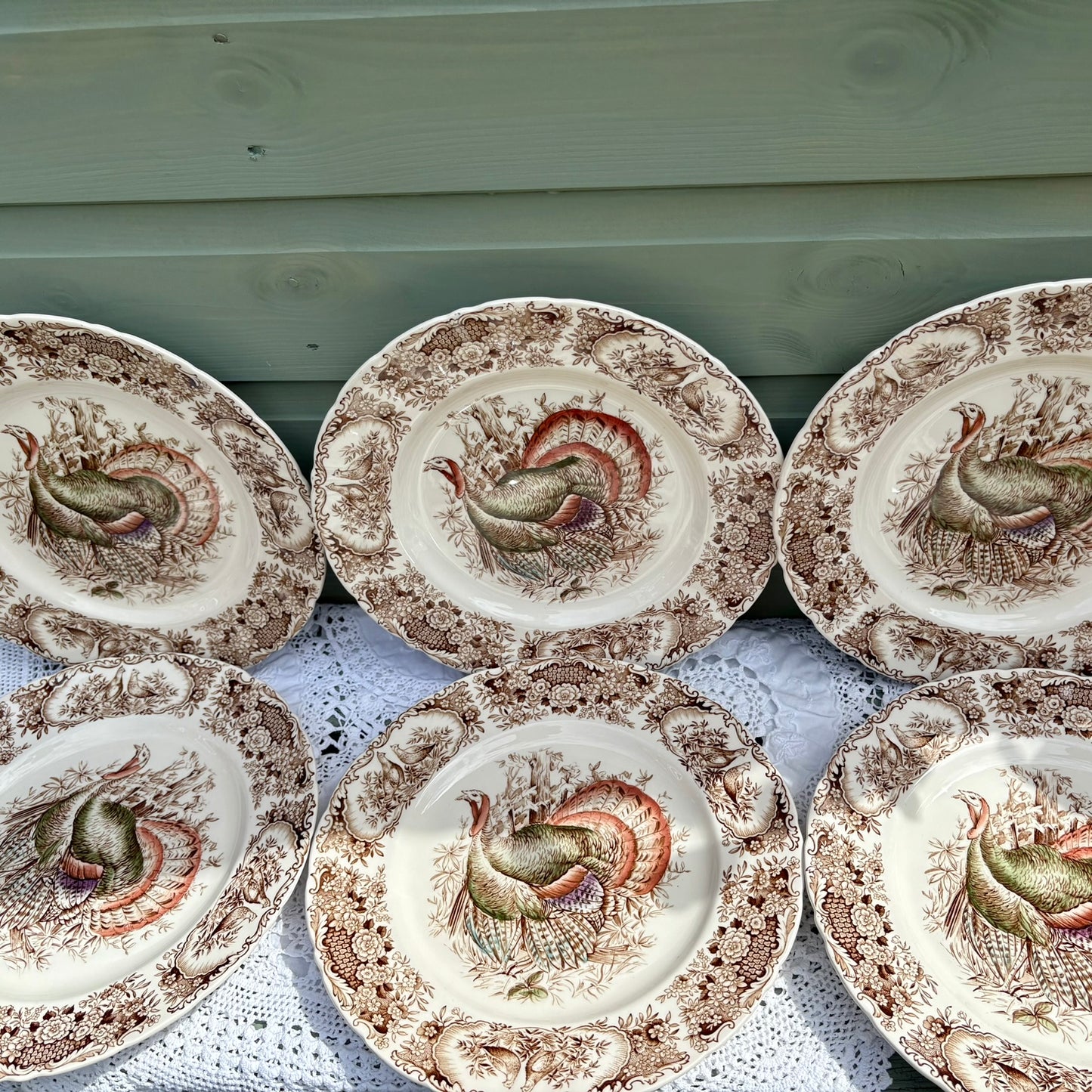 Set of ceramic plates with rooster designs on a wooden surface.