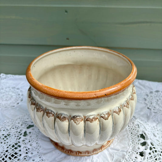 Ceramic pot with ribbed design on a lace tablecloth