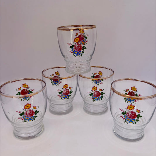 Set of five glass tumblers with floral designs on a white background