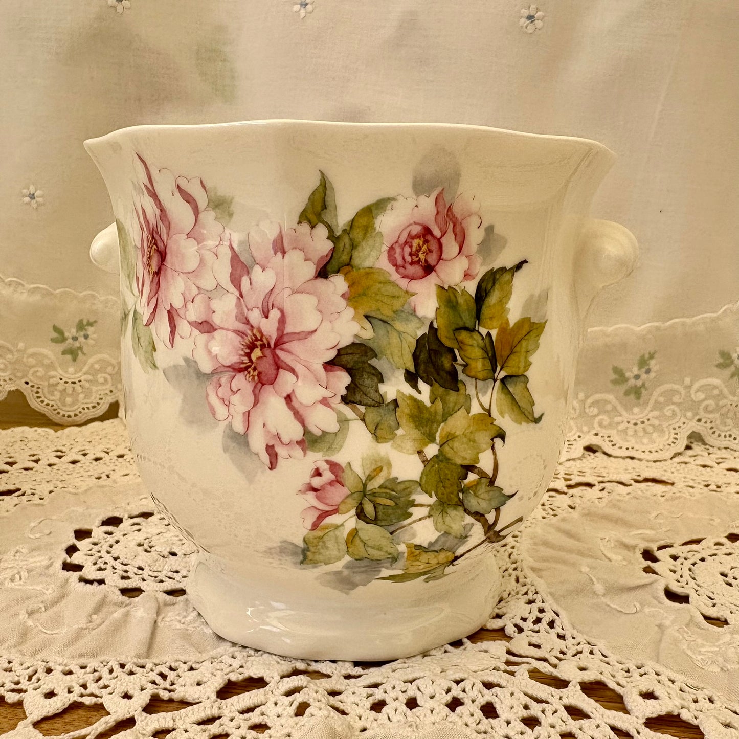 Decorative ceramic vase with floral design on a lace tablecloth
