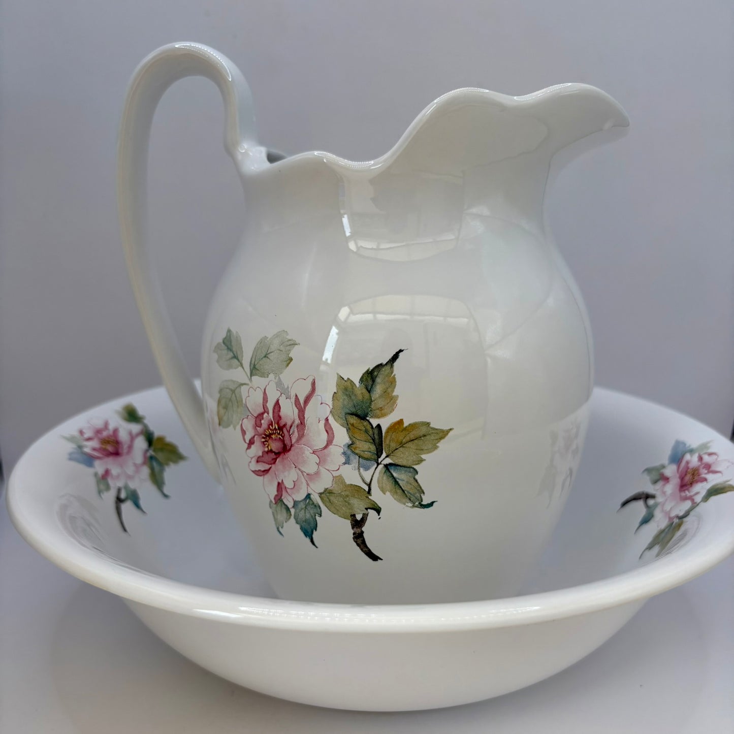 White ceramic pitcher and bowl with floral designs on a white background