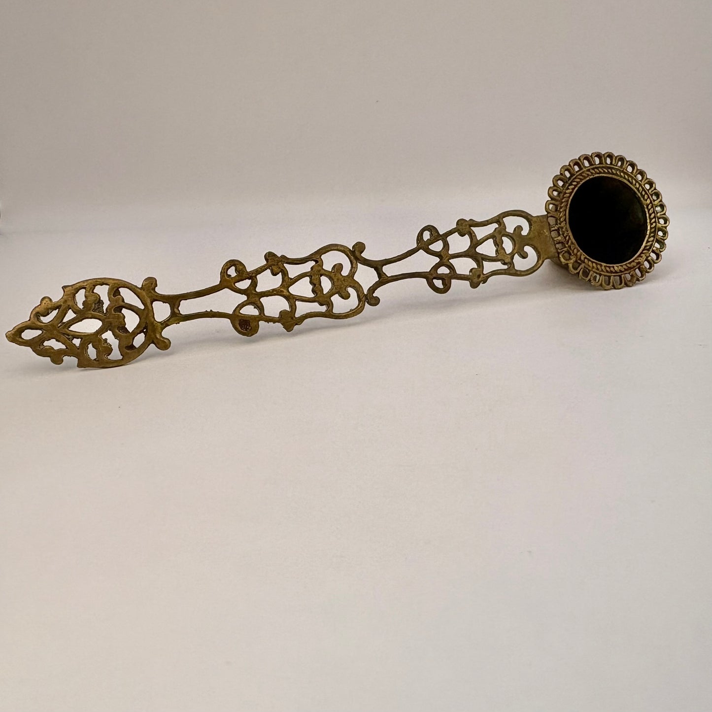 Decorative bronze spoon with intricate designs on a white background