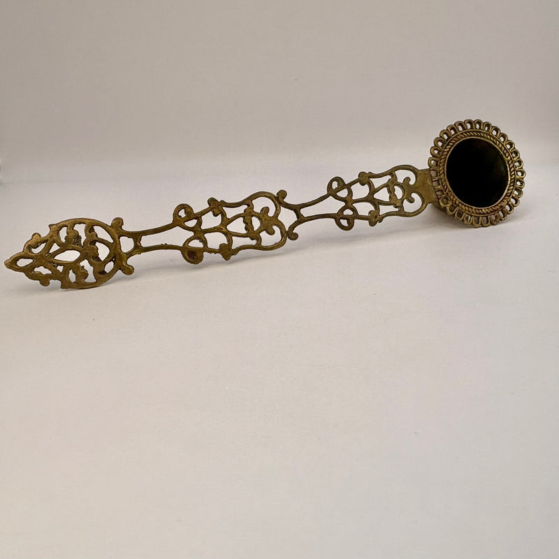 Decorative bronze spoon with intricate designs on a white background