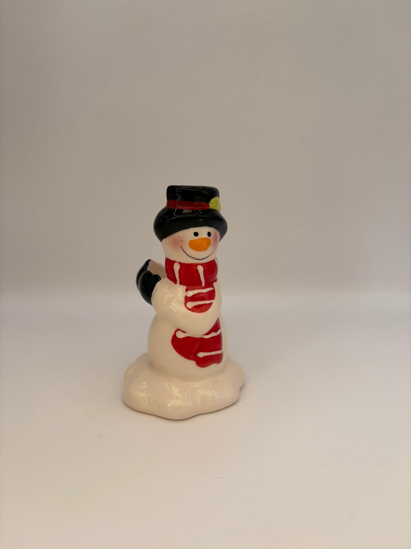Small snowman figurine with a red scarf on a white background