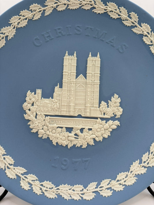 Decorative plate with a Christmas design featuring a cathedral and the year 1977, on a blue background.