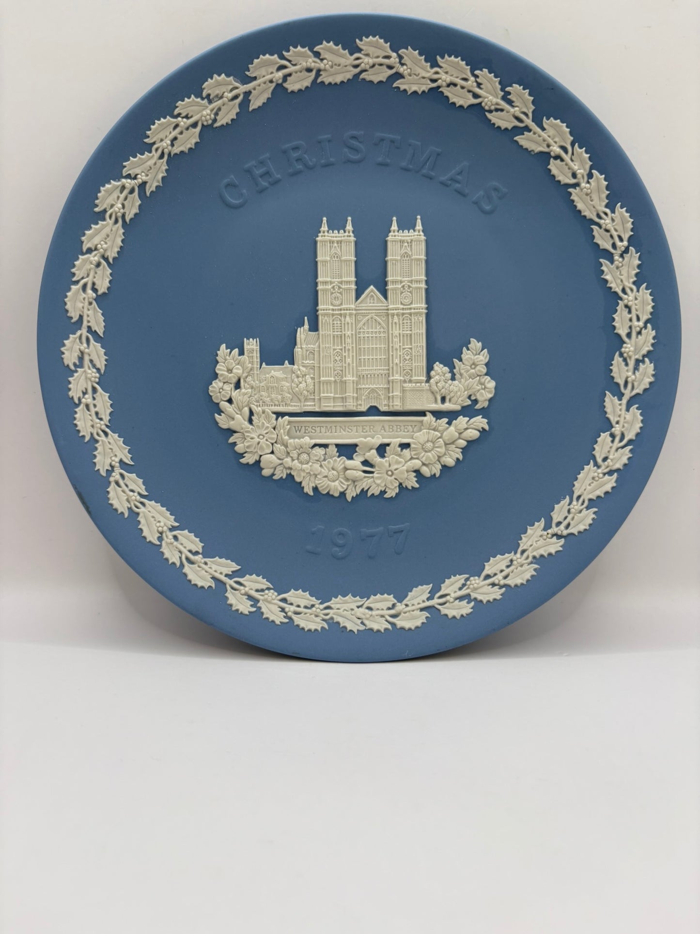 Decorative plate with a Christmas design featuring a building and wreath on a blue background