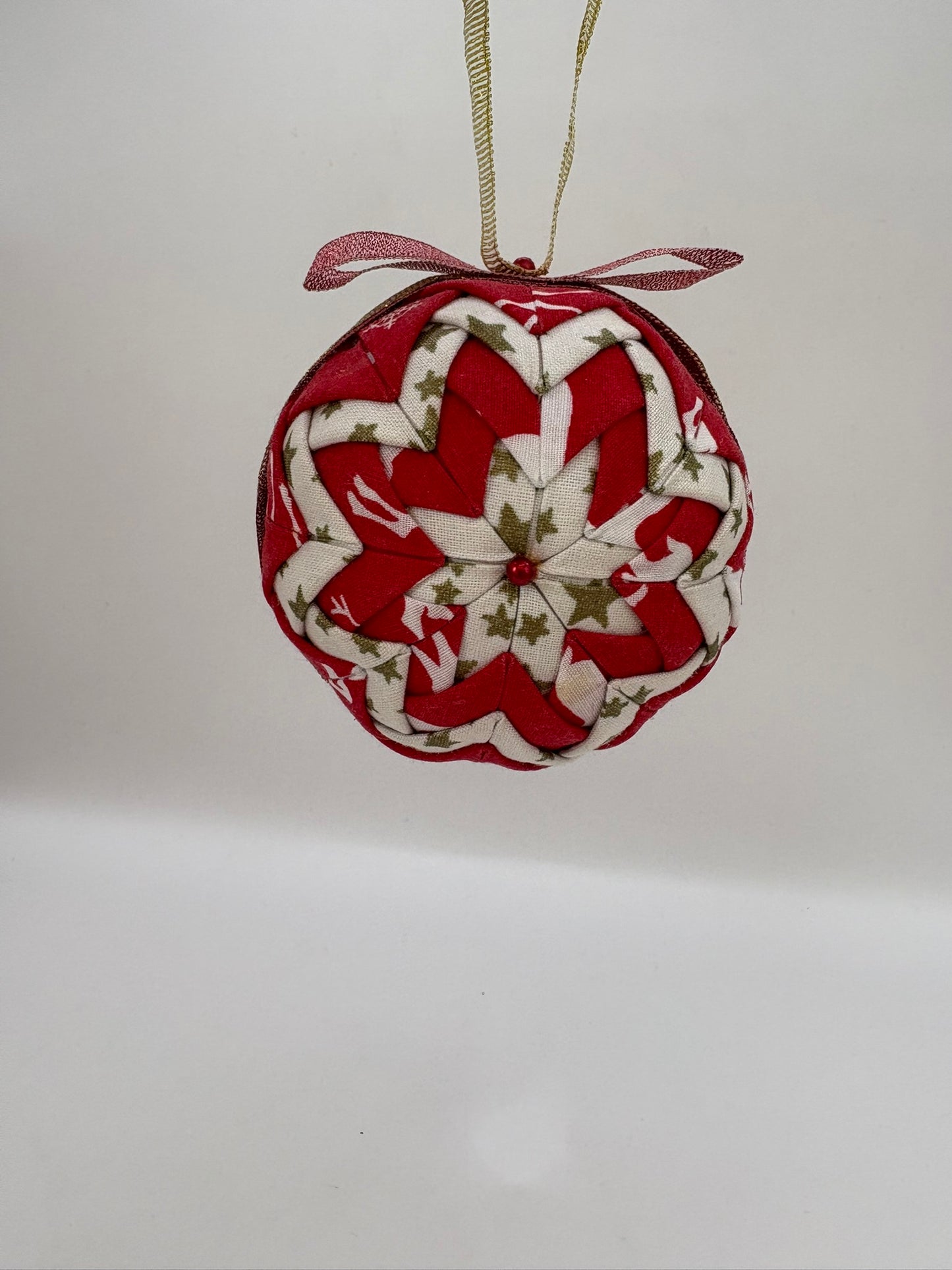 Heart-shaped fabric ornament with red and white pattern on a plain background