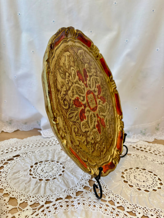 Decorative gold and red oval plate on a white lace surface