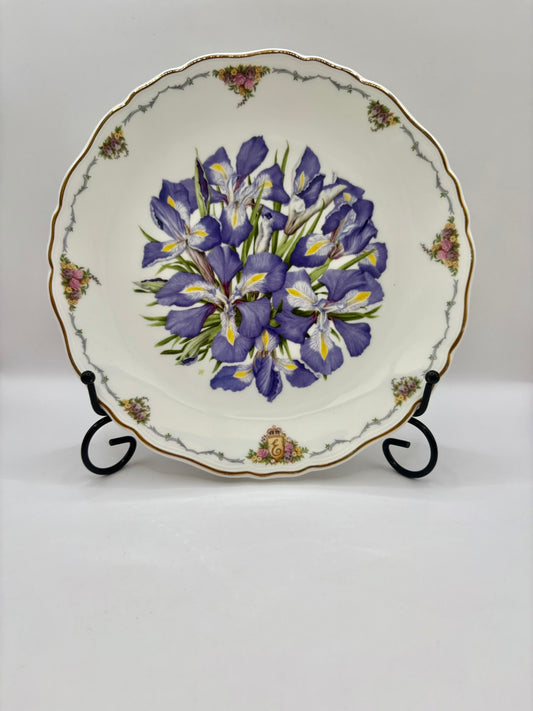 Decorative plate with purple floral design on a stand against a white background