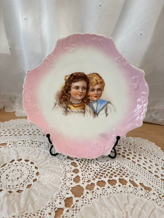 Decorative plate with a vintage illustration of two children on a lace doily.