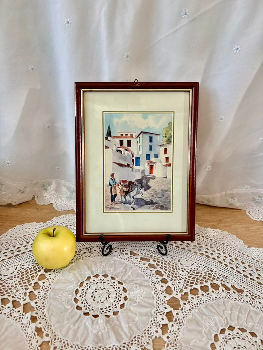Framed artwork on a lace tablecloth with an apple beside it
