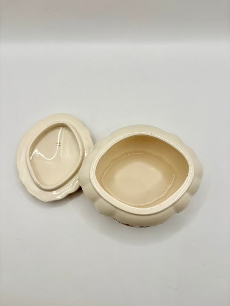 Beige ceramic container with lid on a light gray background