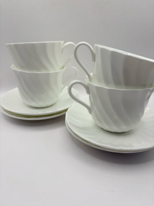 Set of white ceramic cups and saucers on a light gray background