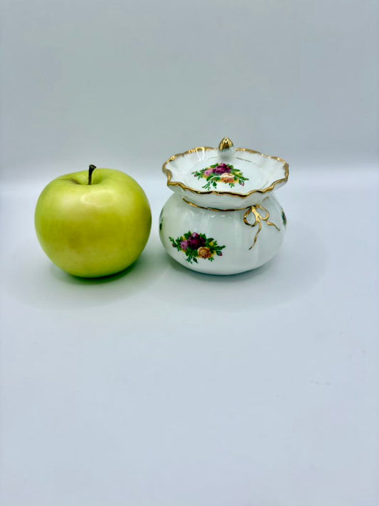 Green apple next to a decorative ceramic pot on a light gray background