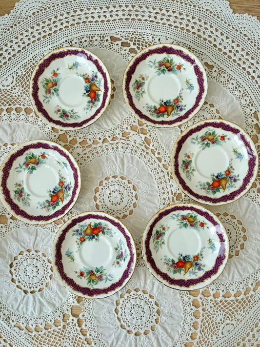 Set of six decorative plates with floral patterns on a lace tablecloth