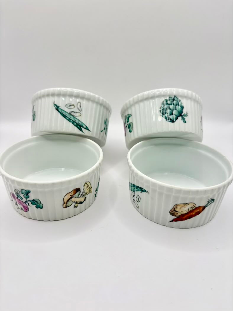 Four white ramekins with colorful illustrations on a white background