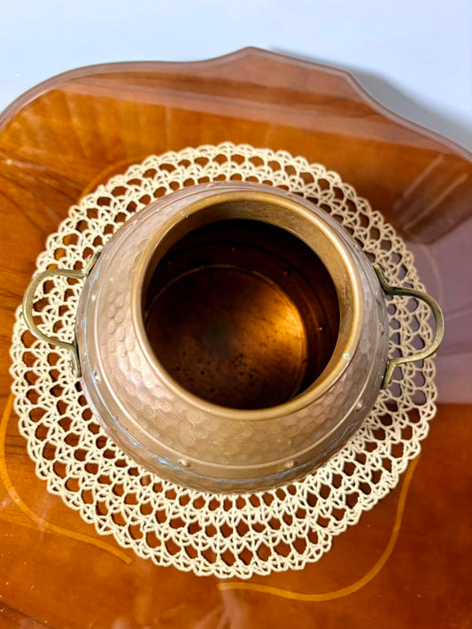 Decorative vase with a doily on a wooden surface