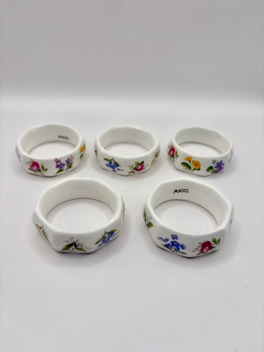 Set of five ceramic napkin rings with floral designs on a white background