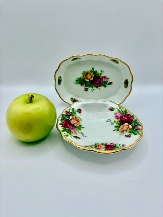 Decorative ceramic dish with floral design next to a green apple on a white background