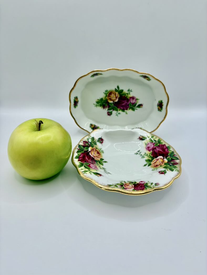 Decorative ceramic dish with floral design next to a green apple on a white background