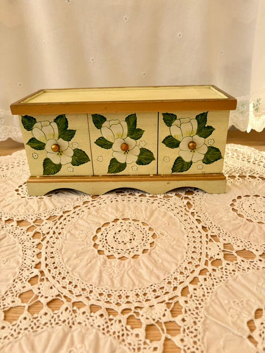 Decorative wooden box with floral designs on a lace tablecloth