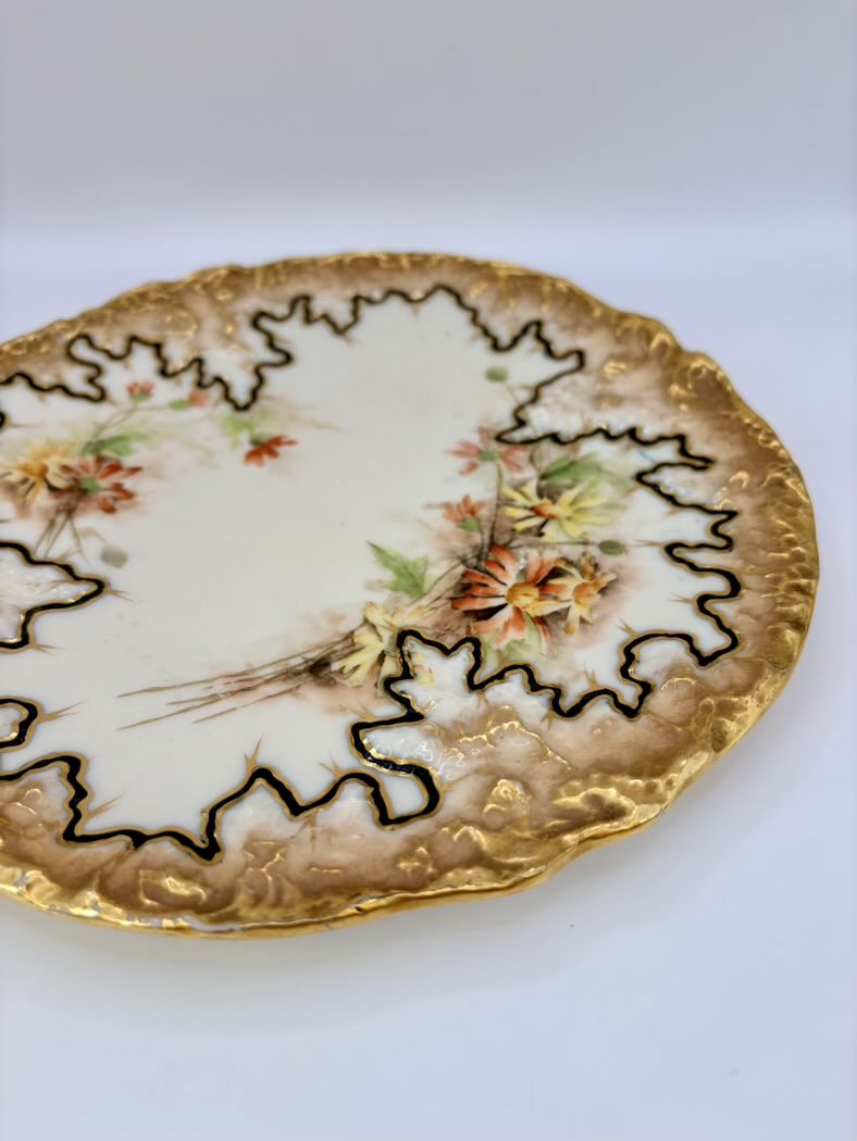 Decorative plate with floral design and gold trim on a white background